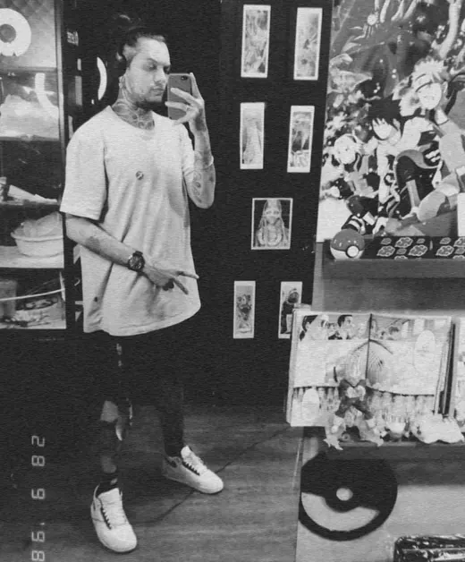 Michael Douglas numa selfie no espelho de uma loja geek, com pôster de Naruto, Pokébola e boneco do Vegeta