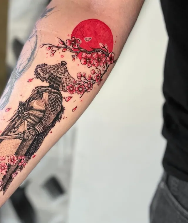 Tatuagem de samurai com chapéu de palha, sol vermelho e flor de cerejeira, interno do antebraço, blackwork com detalhe em vermelho